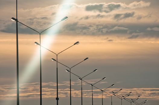 Row of streetlights at evening time with cloudscape on background