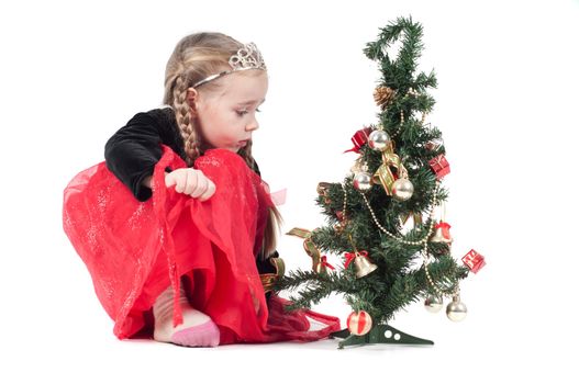 Cute girl sitting with christmas tree on white