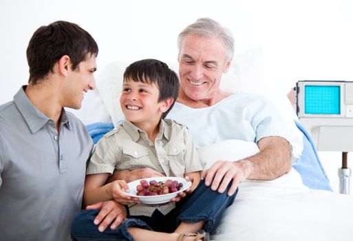 Smiling father and his son visiting grandfather at the hospital