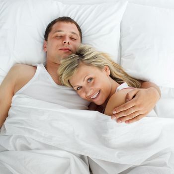 Young woman lying in bed with a boy smiling at the camera