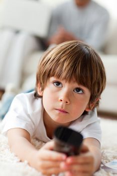 Concentrated little boy watching TV lying on the floor in the living-room