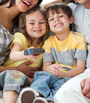 Adorable children watching TV with their parents in the living-room