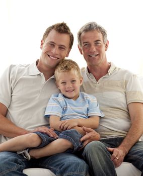 Smiling portrait of son, father and grandfather sitting on sofa