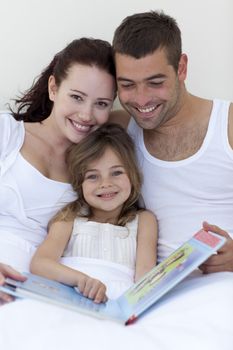 Parents and daughter reading together in bed
