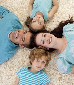 Happy family lying on floor in a circle with heads together