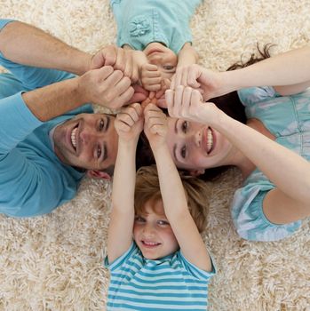 High angle of family lying on floor in a circle with heads and hands together