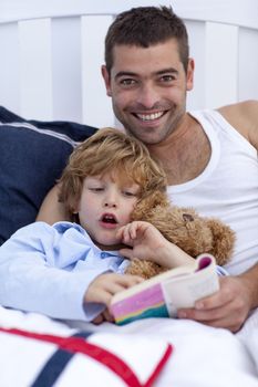 Father and son reading a book in bed together