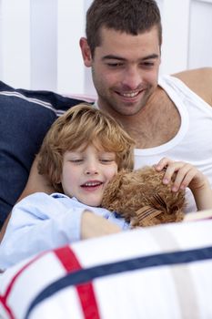 Portrait of father and son reading a book in bed together