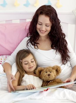 Mother and daughter reading a book together in bed