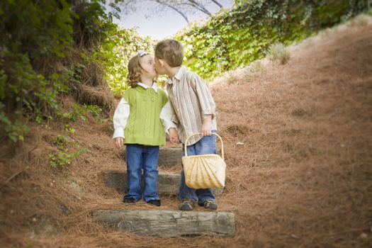 Adorable Brother and Sister Children with Basket Kissing Outside.