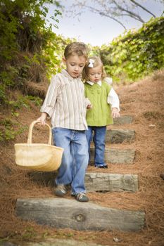 Adorable Brother and Sister Children Holding Hands Walking Down Wood Steps with Basket Outside.