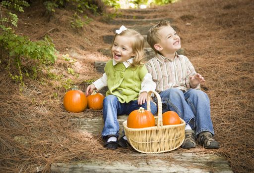 Cute Young Brother and Sister Children Sitting on Wood Steps Laughing with Pumpkins in a Basket.