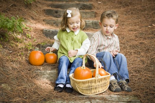 Cute Young Brother and Sister Children Sitting on Wood Steps Laughing with Pumpkins in a Basket.