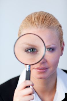 Young Serious Business woman looking through a magnifying Glass
