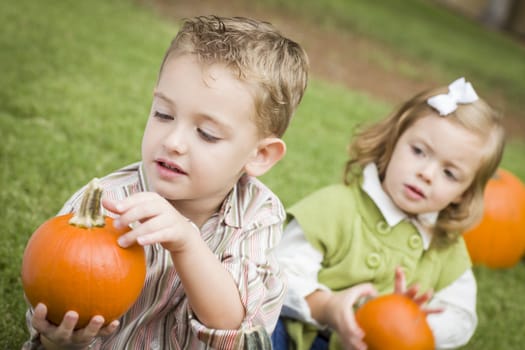 Cute Young Brother and Sister Children Enjoying the Pumpkins at the Pumpkin Patch.