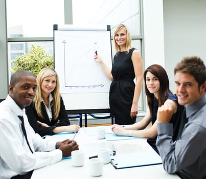 Attractive businesswoman giving a presentation to her team smiling at the camera