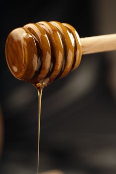 Natural golden honey oozing from a wooden drizzler