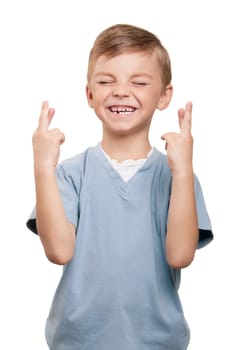 Portrait of superstitious little boywith crossed fingers over white background