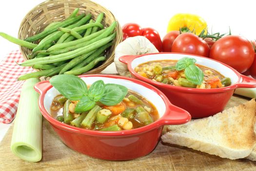 Minestrone with tomatoes, beans, carrots, potatoes and leeks on a light background