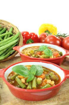 Minestrone with tomatoes, peppers, carrots, potatoes and beans on a bright background