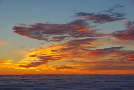 Sunrise in fire from the top of mountains. The valley below is filled with clouds and it's called sea of clouds or sea of mist.