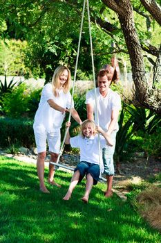 Happy family having fun swinging  in the garden