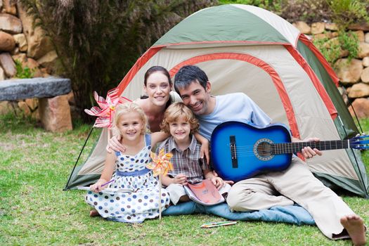 Happy family camping and playing a guitar