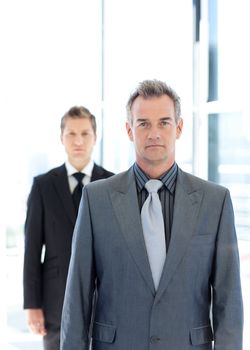 Senior and young businessmen looking to the camera in an office