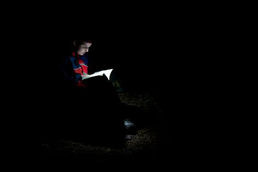 A woman reading an old book in the dark