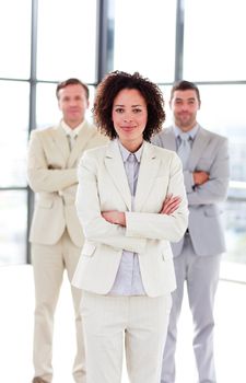 Attractive businesswoman with folded arms with her team in the background