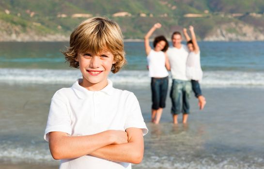 Blond boy on a beach with his parents and his sister in background