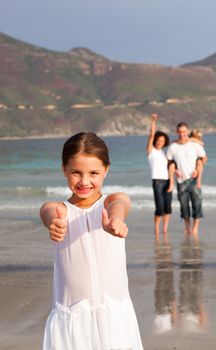 Cheerful girl on a beach with her parents and her brother in background