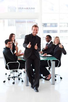 Happy businessman with thumbs up in a meeting