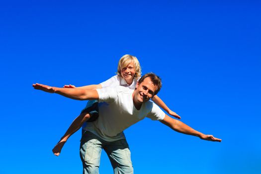 Young boy on father's back playing airplane outdoors