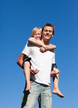 Man giving young boy piggyback ride outdoors smiling 