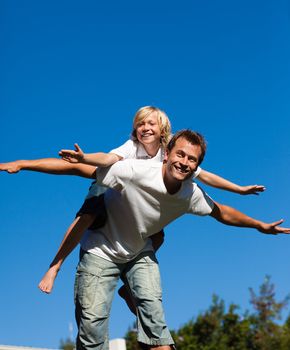 Happy man giving young boy piggyback ride outdoors smiling 