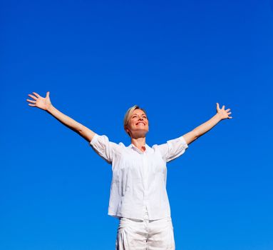 Young woman doing exercises outdoors against blue sky