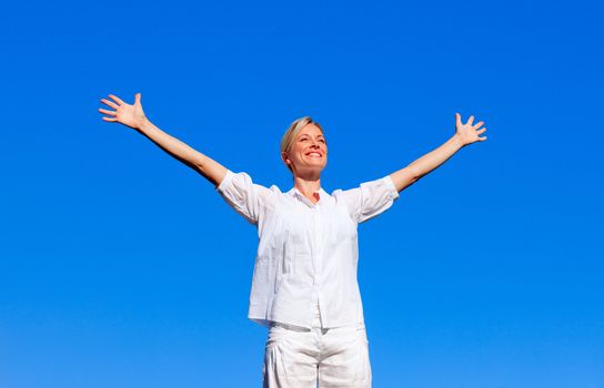 Happy woman feeling free outdoors with open arms