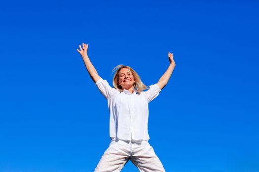 Happy girl jumping outdoors against blue sky