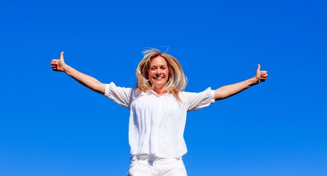 Young woman jumping outdoors against blue sky