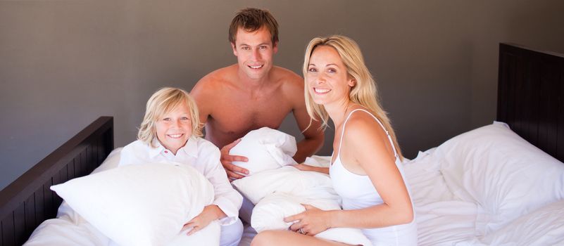 Family playing with pillows in bedroom