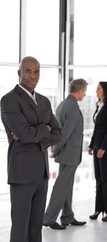 business leader with folded arms looking at camera in front of team 