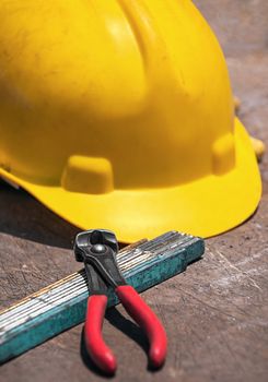 Construction tools - protective helmet, folded ruler, nippers for binding wires -  on construction workshop table