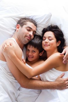 Happy young family lying in bed 