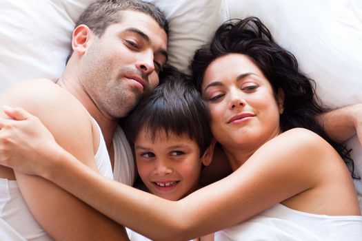 Portrait of a happy young family sleeping in bed 