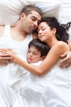 Nice familiy sleeping together in a white bed
