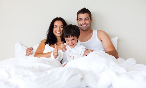 Smiling Kid with thumbs up and his parents in bed