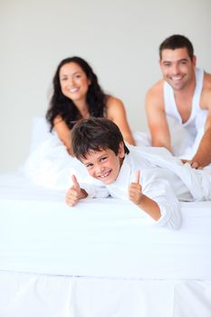 Smiling son with thumbs up playing in bed