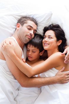 Happy young family resting in bed 