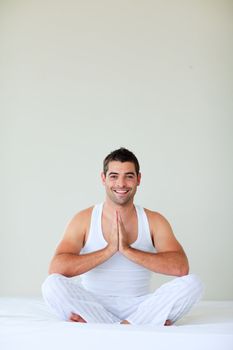 Smiling young man doing yoga in his bedroom